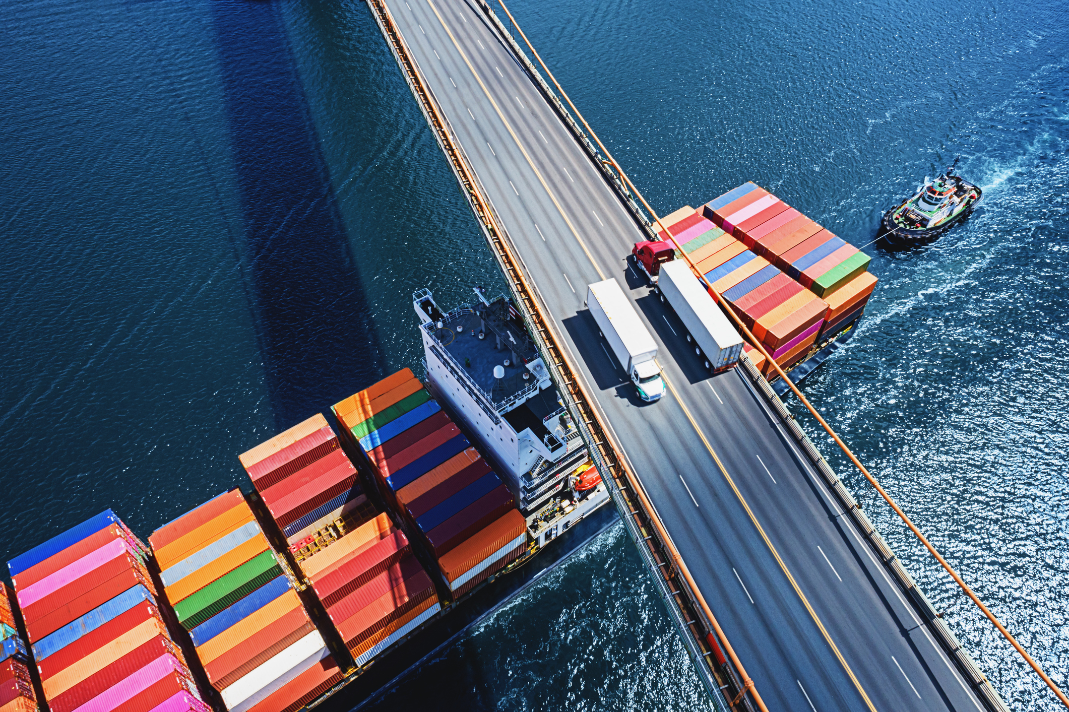 Keyaniyan_Leistungen_Logistik Logistik: Containerschiff unterquert Brücke mit LKWs